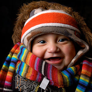 A baby wearing many items of winter clothing: ...