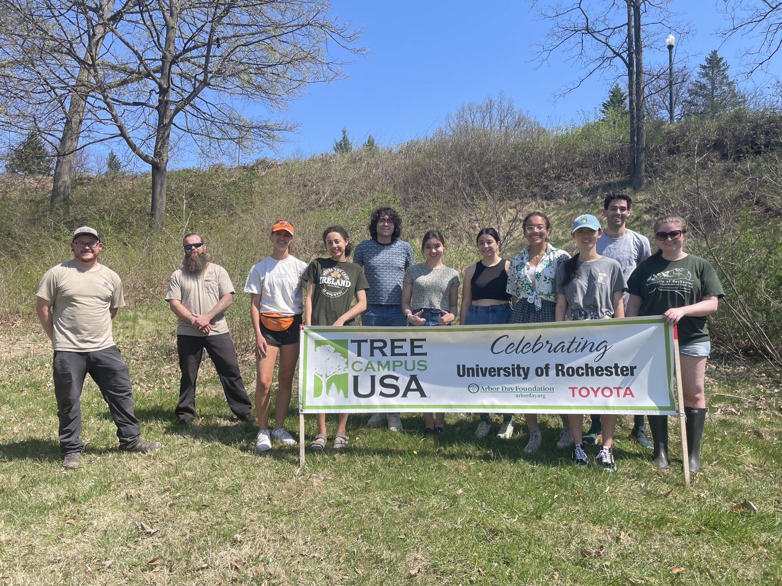 Students and Grounds crew members stand in front of a banner that says Tree Campus USA.