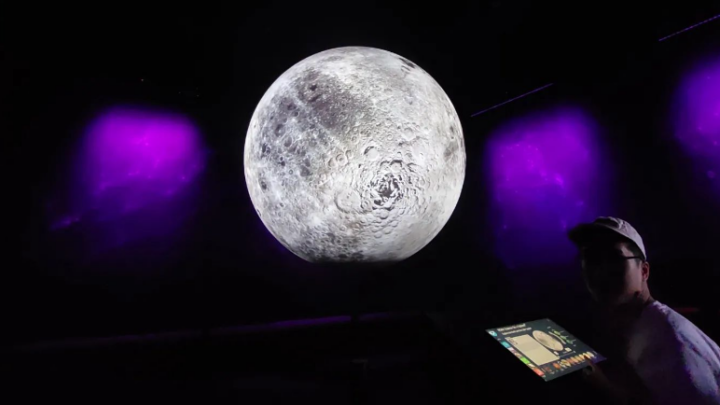 large image of the moon with a student at an editing table