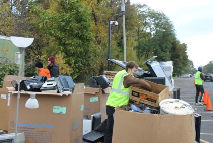volunteers empty boxes of electronics into large bins and containers to be safely and securely recycled