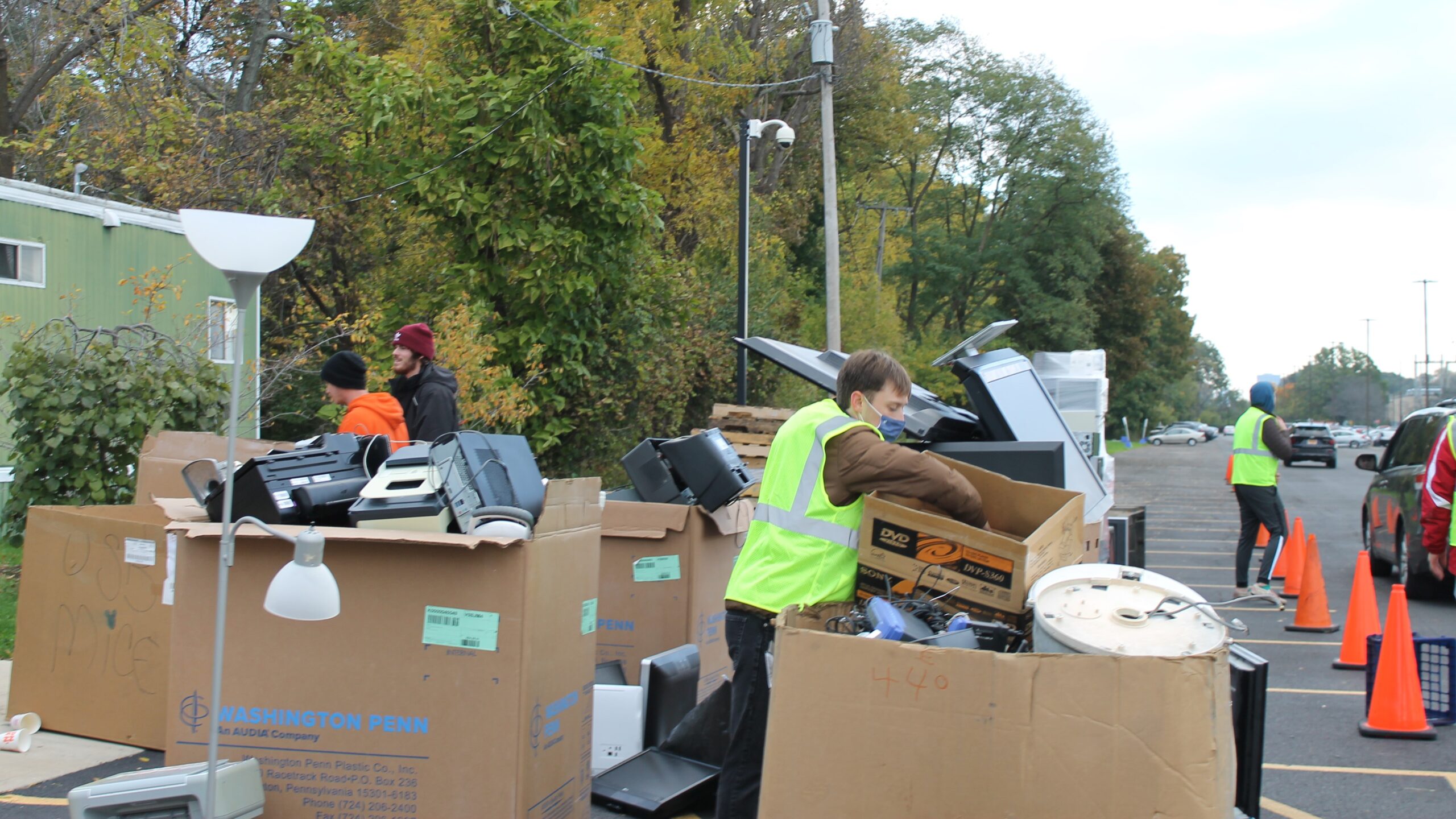 volunteers empty boxes of electronics into large bins and containers to be safely and securely recycled