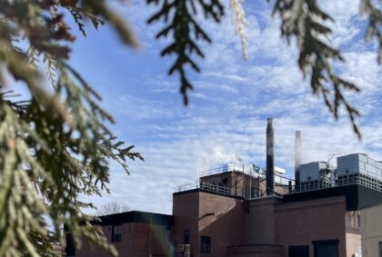 image of University power plant with a blue sky and evergreens in the background and foreground